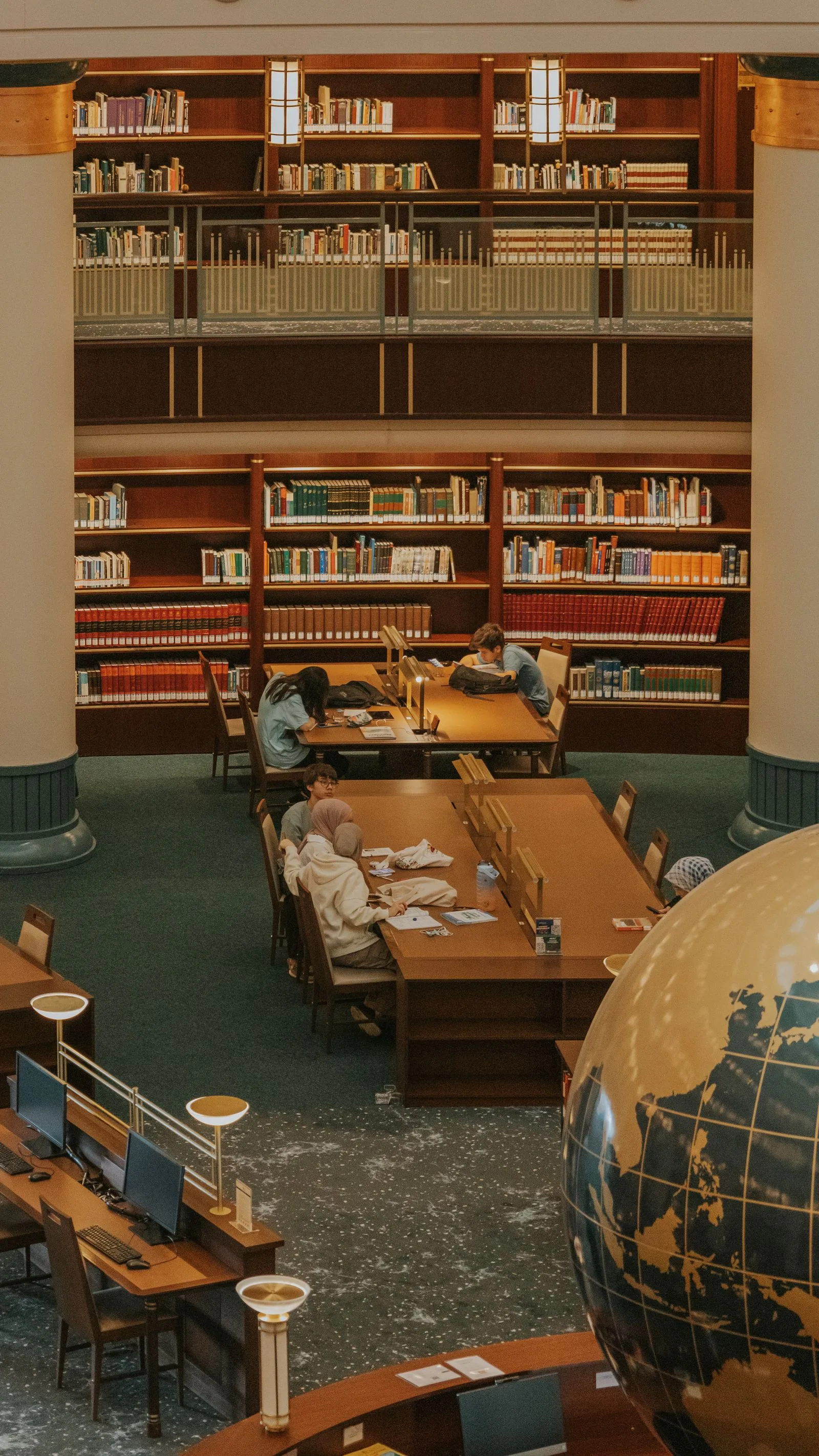 Students studying at long tables in a university library