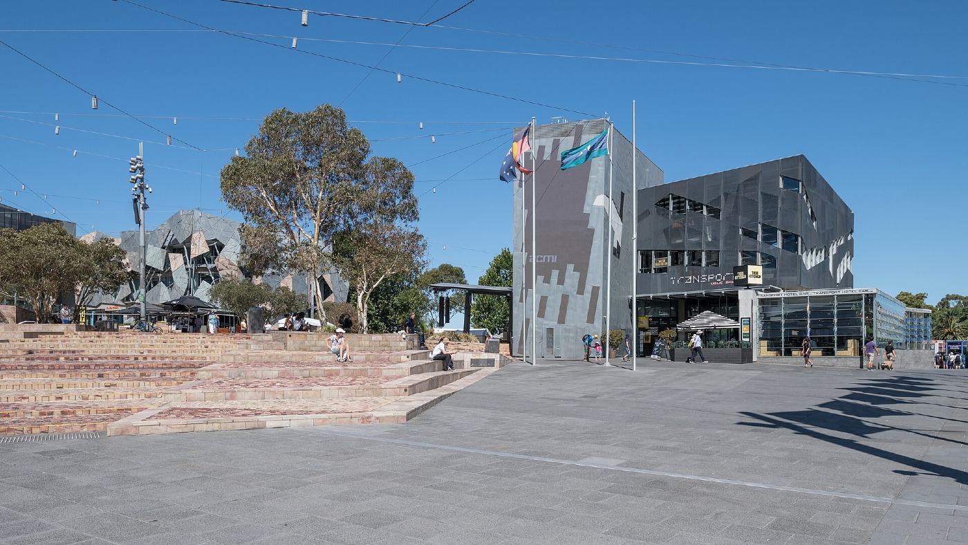 Federation Square in Melbourne on a sunny day, with people crossing the square