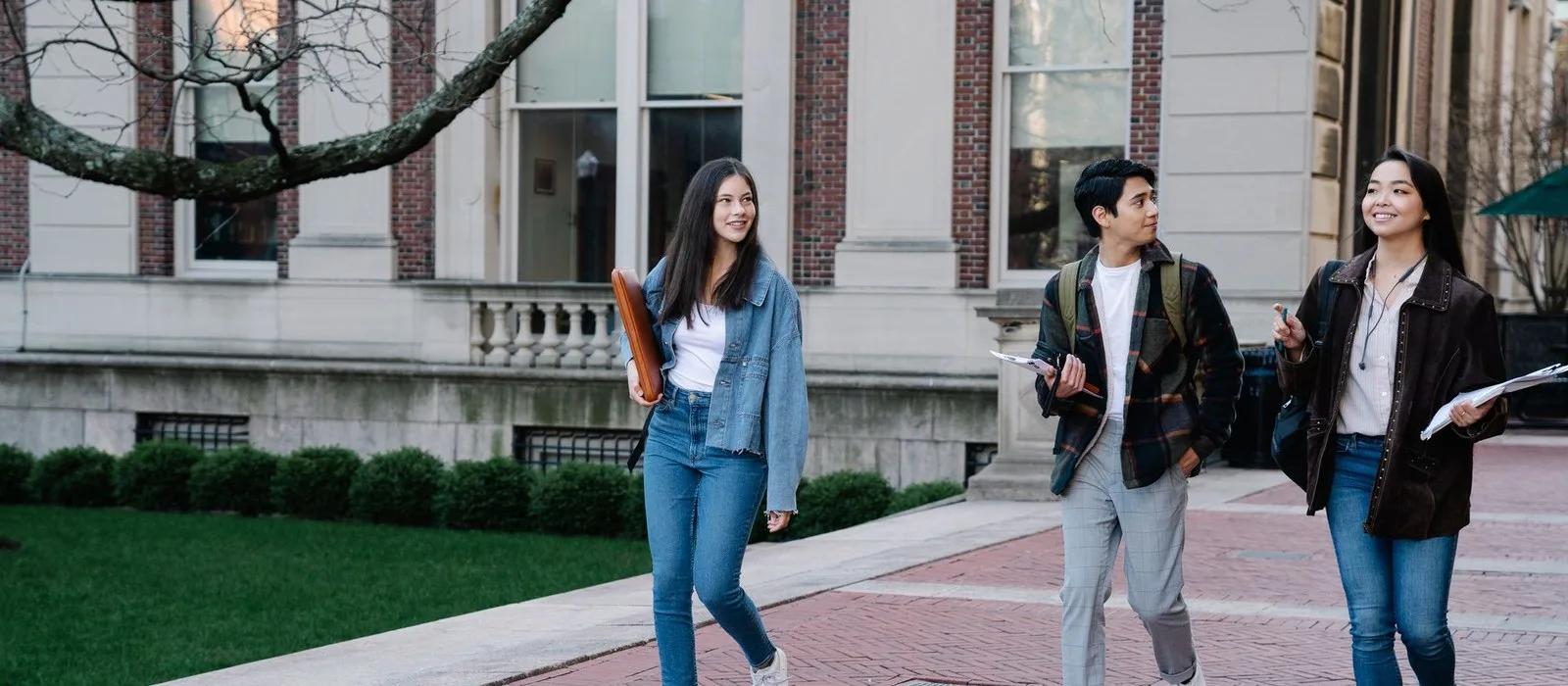 Three students walking together across a university campus