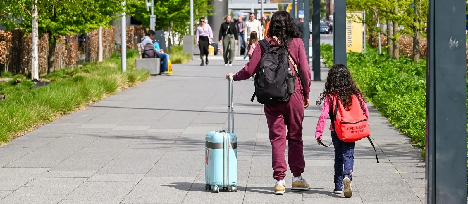 A mother and daughter walking with luggage to the airport